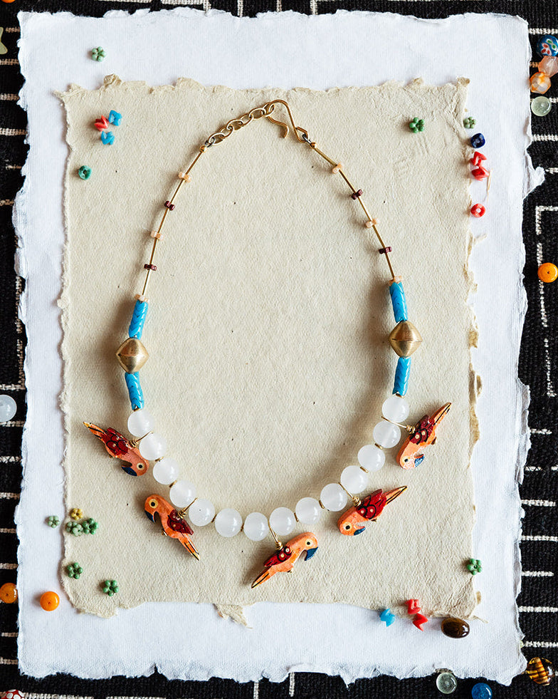 Necklace with colorful beads on a textured card against a black and white patterned background