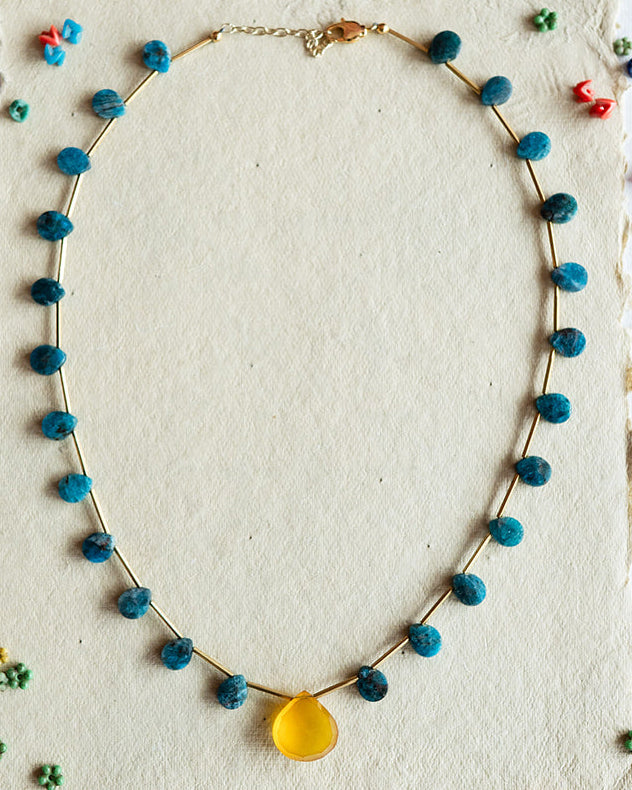Necklace with colorful beads on a white card against a black patterned background