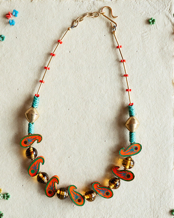 Necklace with colorful beads on a textured card against a black and white patterned background
