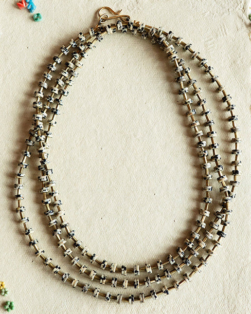 Necklace displayed on a white card with colorful beads on a black textured background