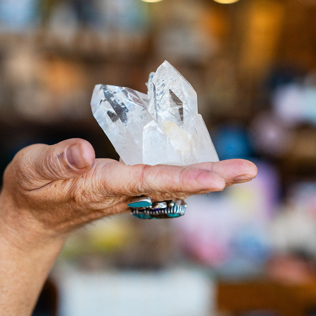 Hand holding a crystal formation with a blurred indoor background