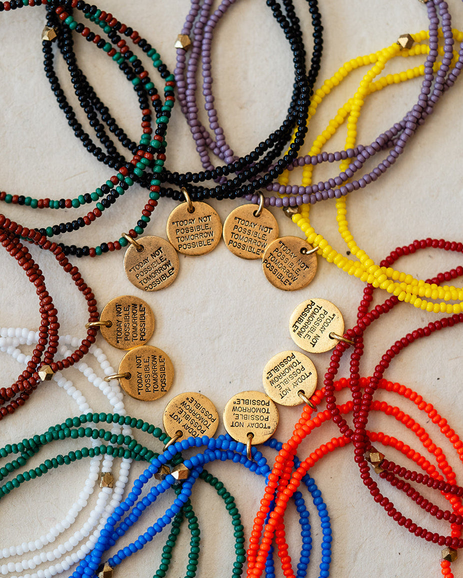Colorful beaded bracelets with gold charms on a light background