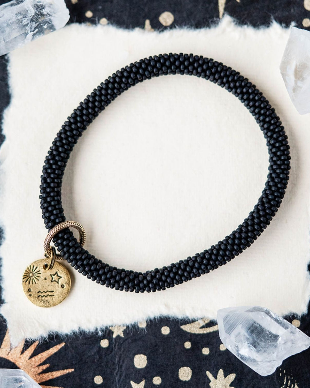 Black beaded bracelet with gold Aquarius zodiac charm styled with clear crystals and celestial elements