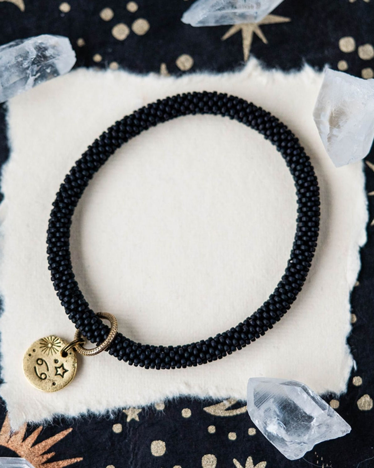 Black beaded bracelet with gold Cancer zodiac pendant styled with crystals and celestial elements