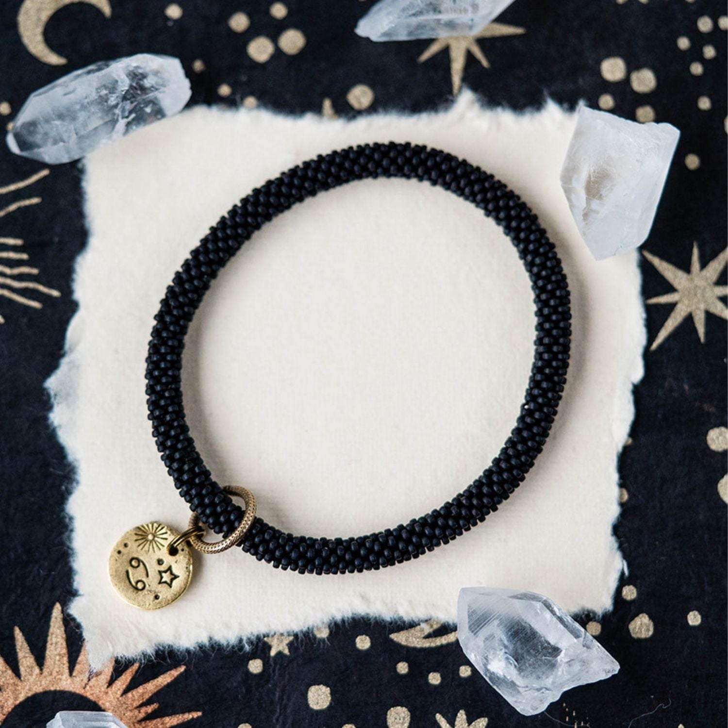 Black beaded bracelet with gold Cancer zodiac pendant styled with crystals and celestial elements