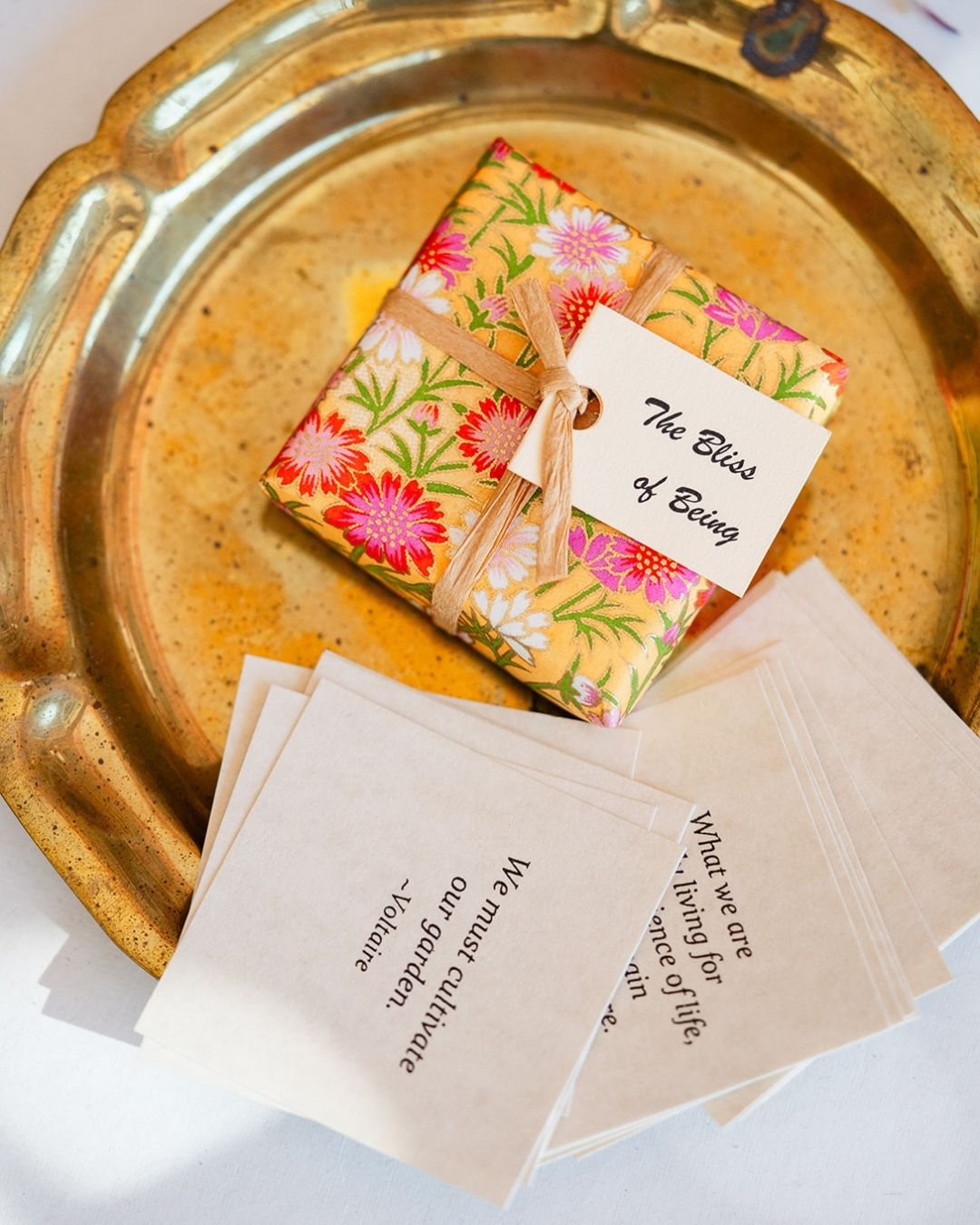 Colorful 'The Bliss of Being' book with information cards displayed on decorative gold tray.