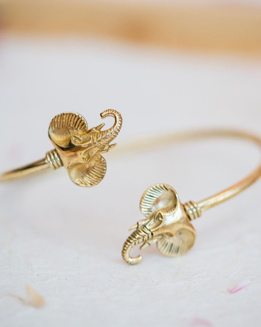 Two brass elephant cuffs displayed on white surface showing delicate trunk and ear details