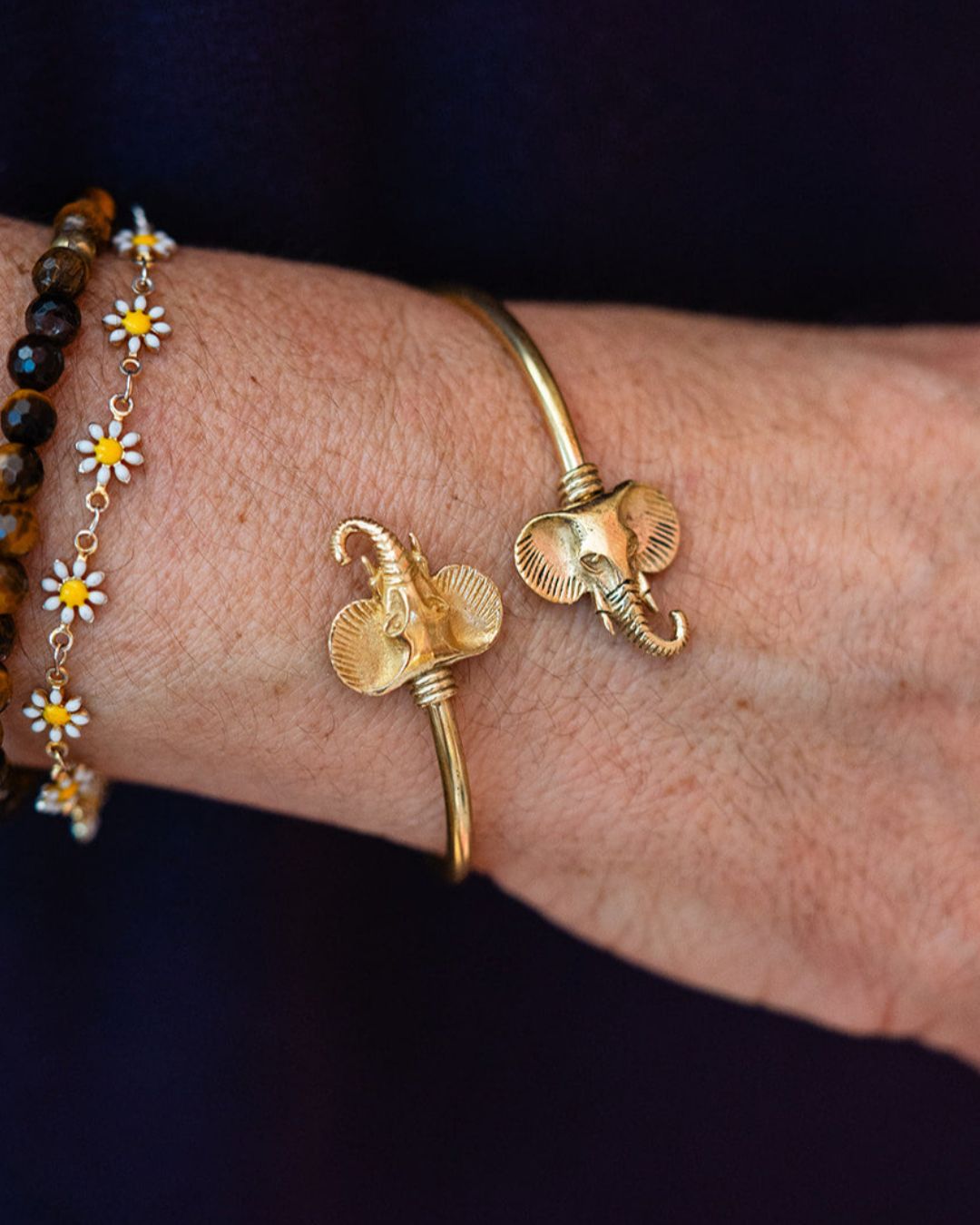 Wrist wearing adjustable brass elephant cuff paired with colorful beaded bracelet