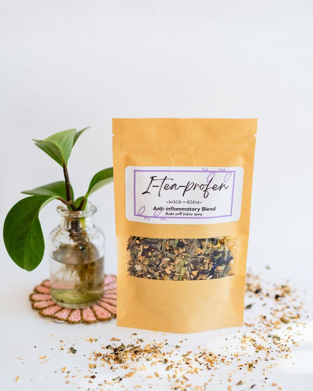 BWG I-tea-profen blend in kraft packet with clever name, displayed with small plant and loose tea sprinkles.