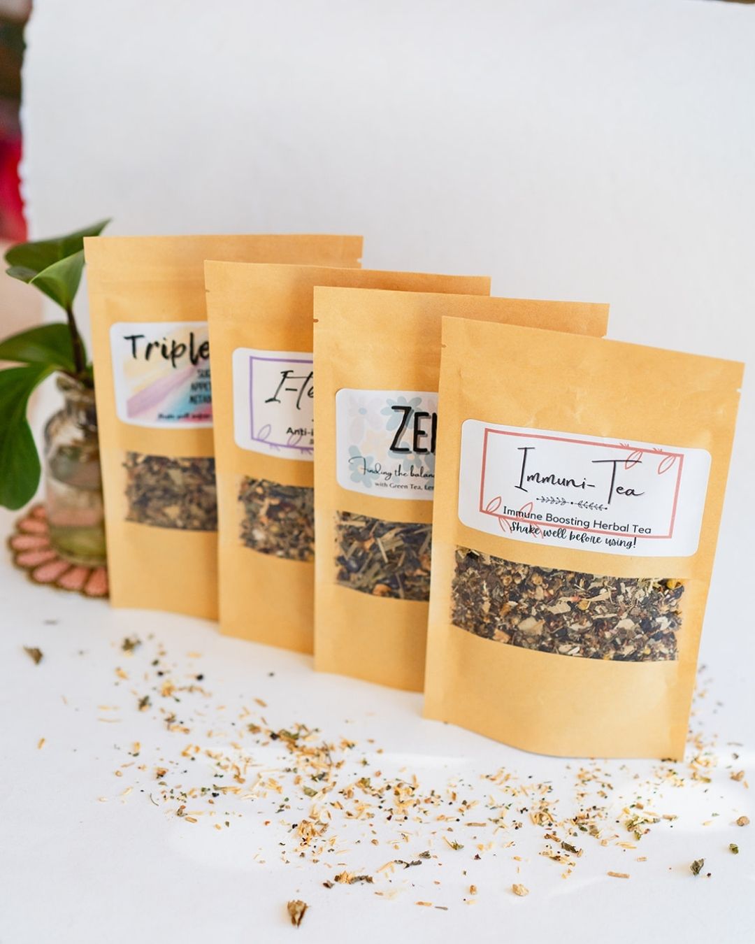Four BWG tea packets in kraft paper pouches lined up showing window display of loose leaf tea blends.