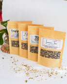 Four BWG tea packets in kraft paper pouches lined up showing window display of loose leaf tea blends.