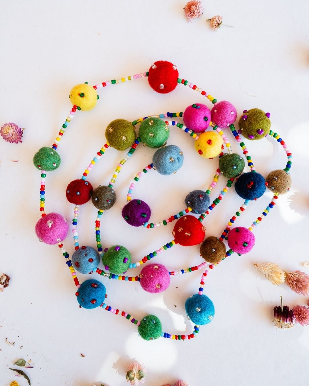 Colorful felted wool ball garland with rainbow beads in jewel tones