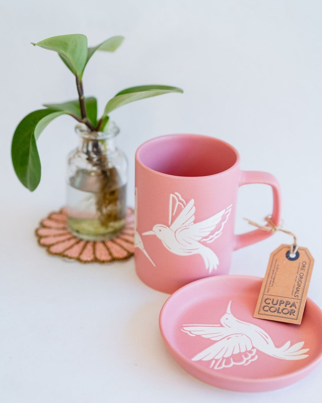 Pink mug with hummingbird design and matching coaster on beaded display