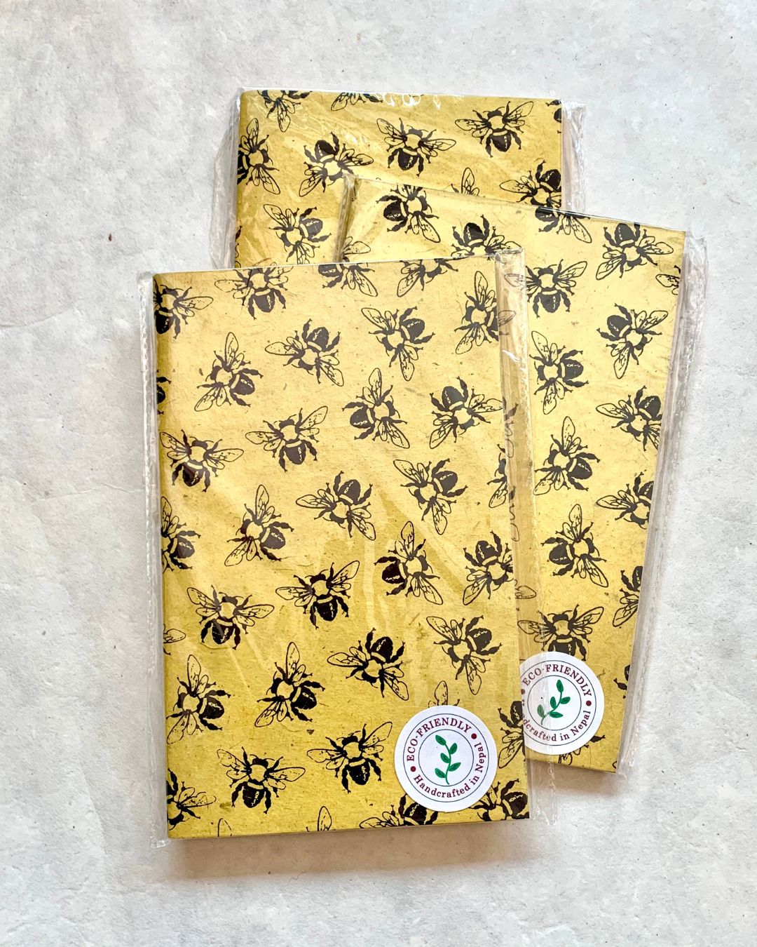 Eco-friendly handcrafted blank journal with yellow background and black bee pattern on cover.