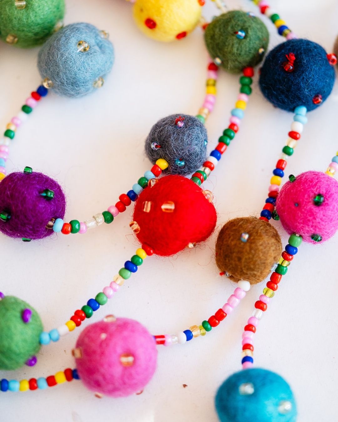 Close-up of felted wool pom pom garland with rainbow seed beads