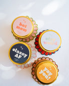 Four GP Candle 4oz tins on colorful beaded coasters featuring fun sayings