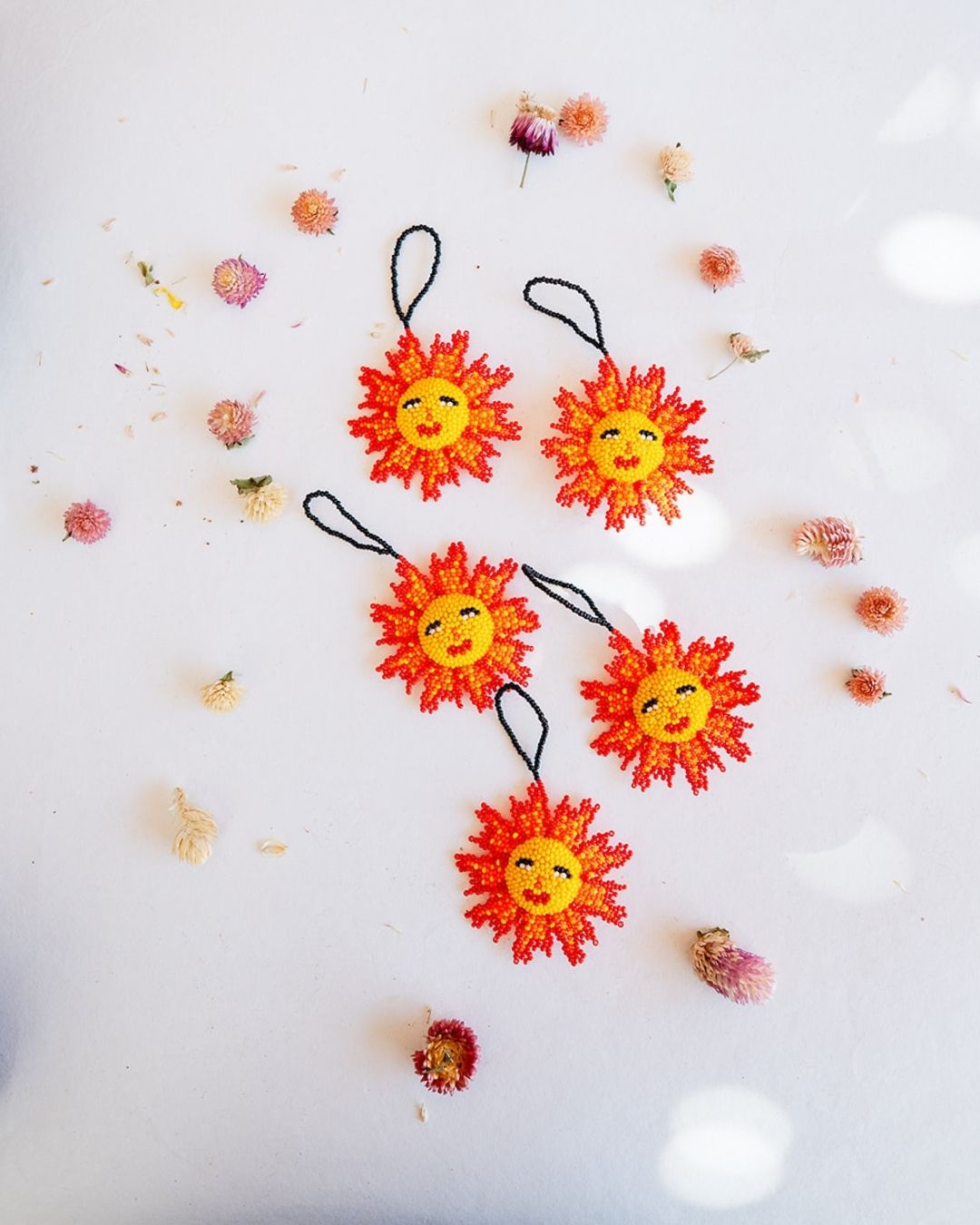 Handcrafted beaded sunshine ornaments with smiling faces in orange and yellow seed beads, five unique pieces