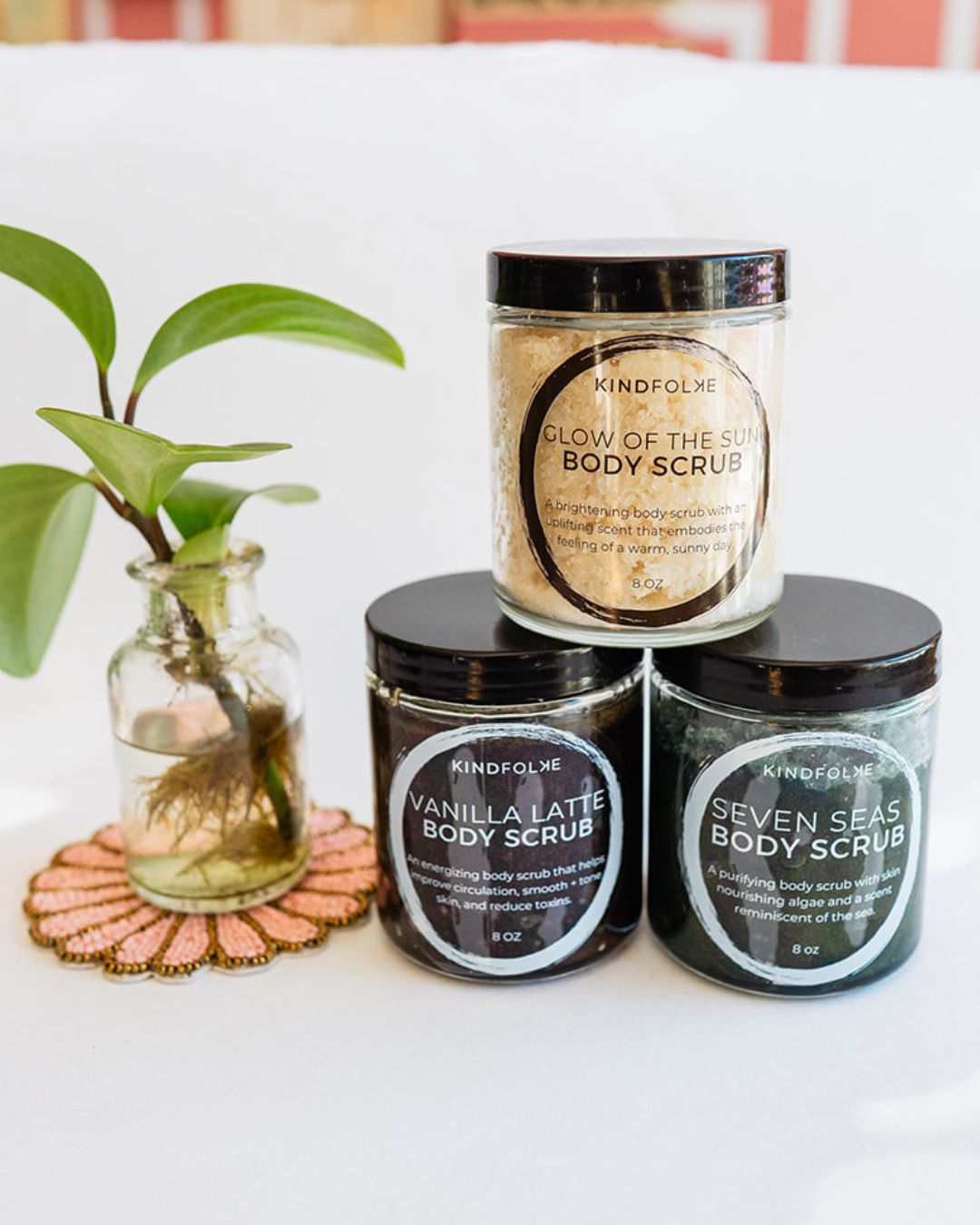 Kindfolke organic body scrub collection with potted plant on beaded coaster