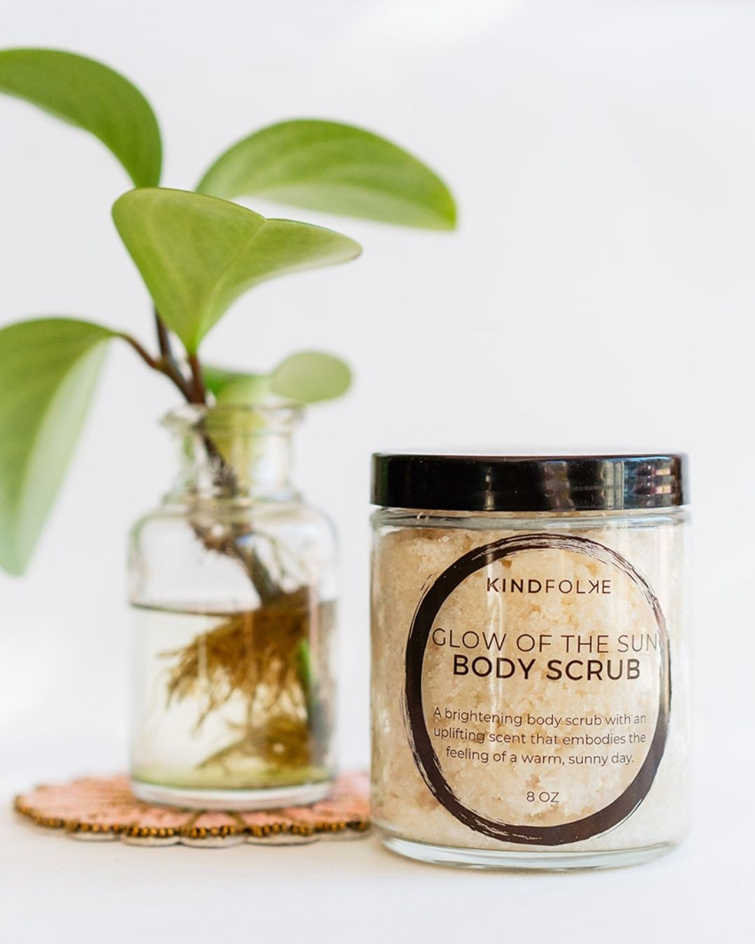 Glow of the Sun brightening body scrub with grapefruit and ginger oils beside plant