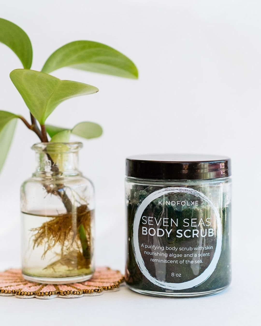 Seven Seas purifying body scrub in glass jar with water plant on beaded coaster