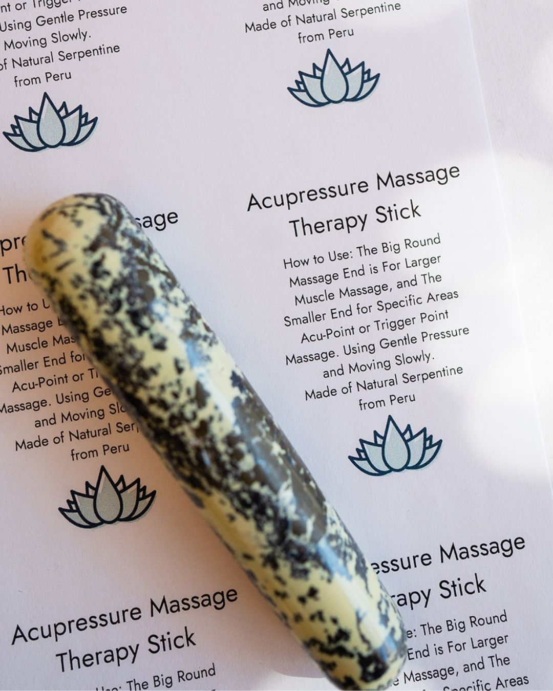 Green serpentine acupressure massage stick on information card with lotus design