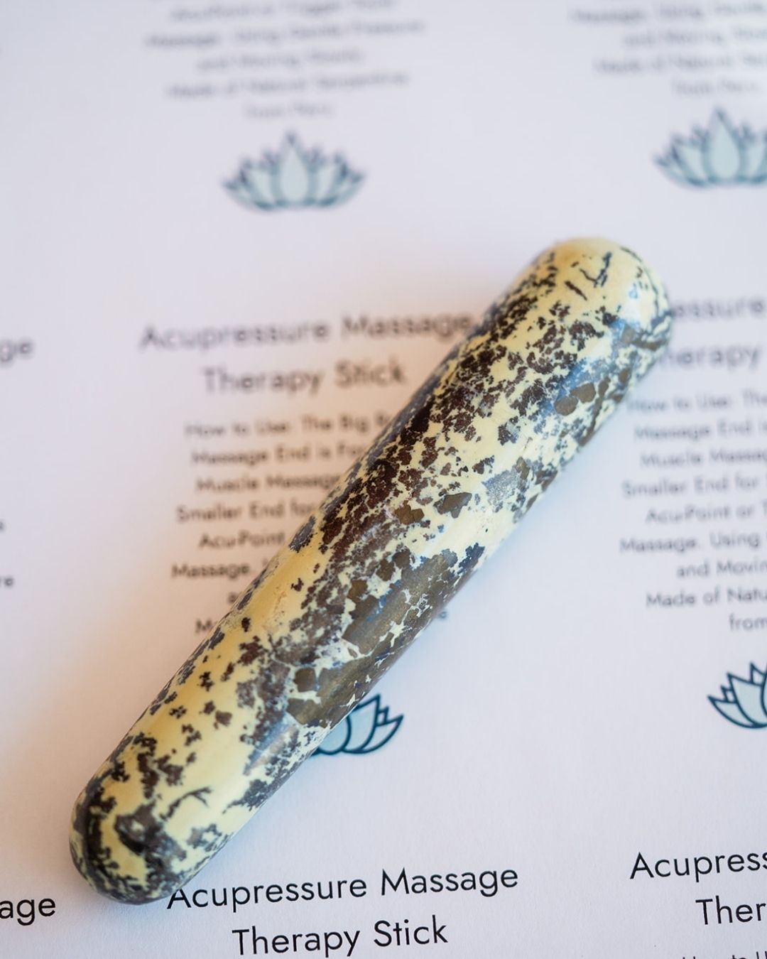 Close-up of serpentine massage stick showing natural green and cream texture with polished finish