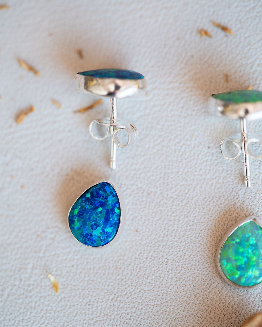 Blue Winter and green Summer sterling silver opal studs highlighted on textured background