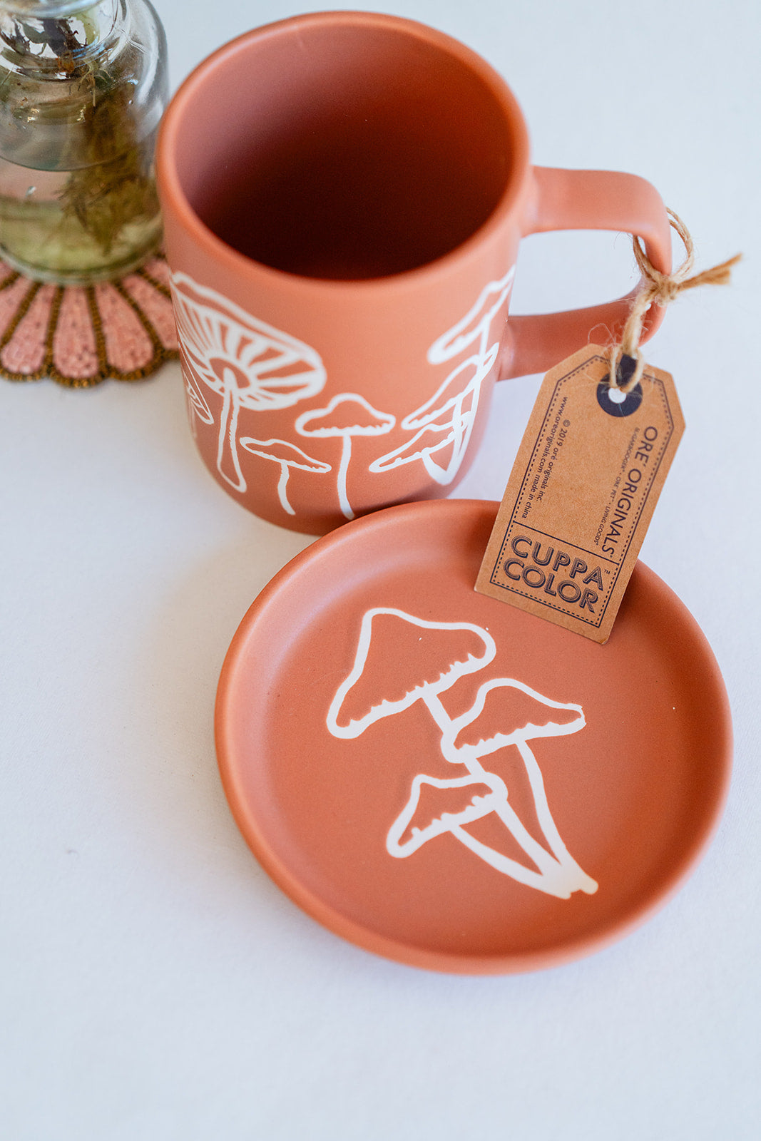 Coral orange Cuppa Color ceramic mug and coaster featuring white mushroom silhouette design, handcrafted premium drinkware