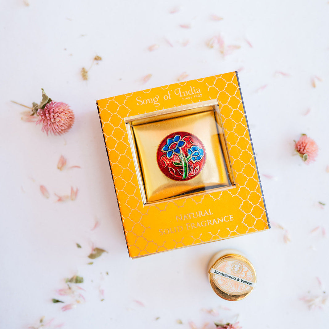Song of India Sandalwood & Vetiver natural solid perfume in vibrant orange box with red brass container featuring blue floral embossed design