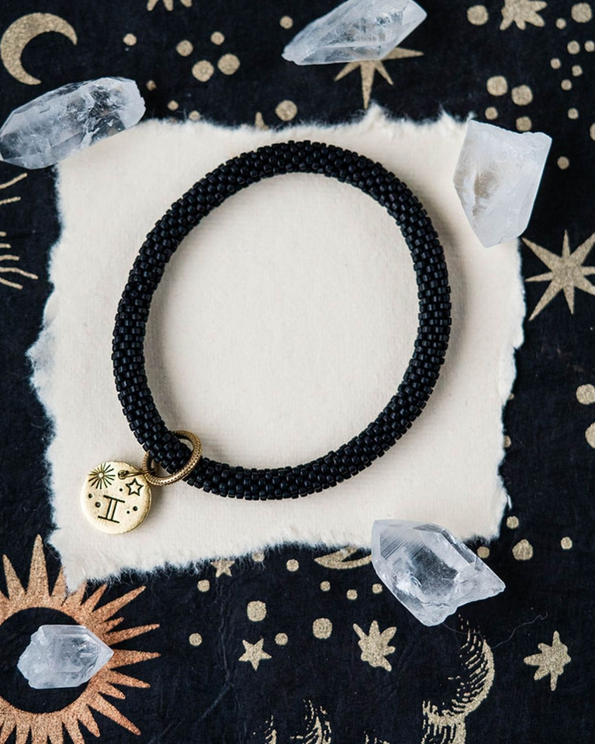 Black beaded bracelet with gold Gemini zodiac pendant styled with crystals and celestial elements