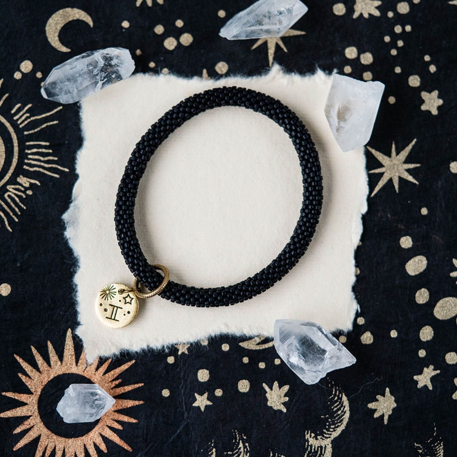 Black beaded bracelet with gold Gemini zodiac pendant styled with crystals and celestial elements