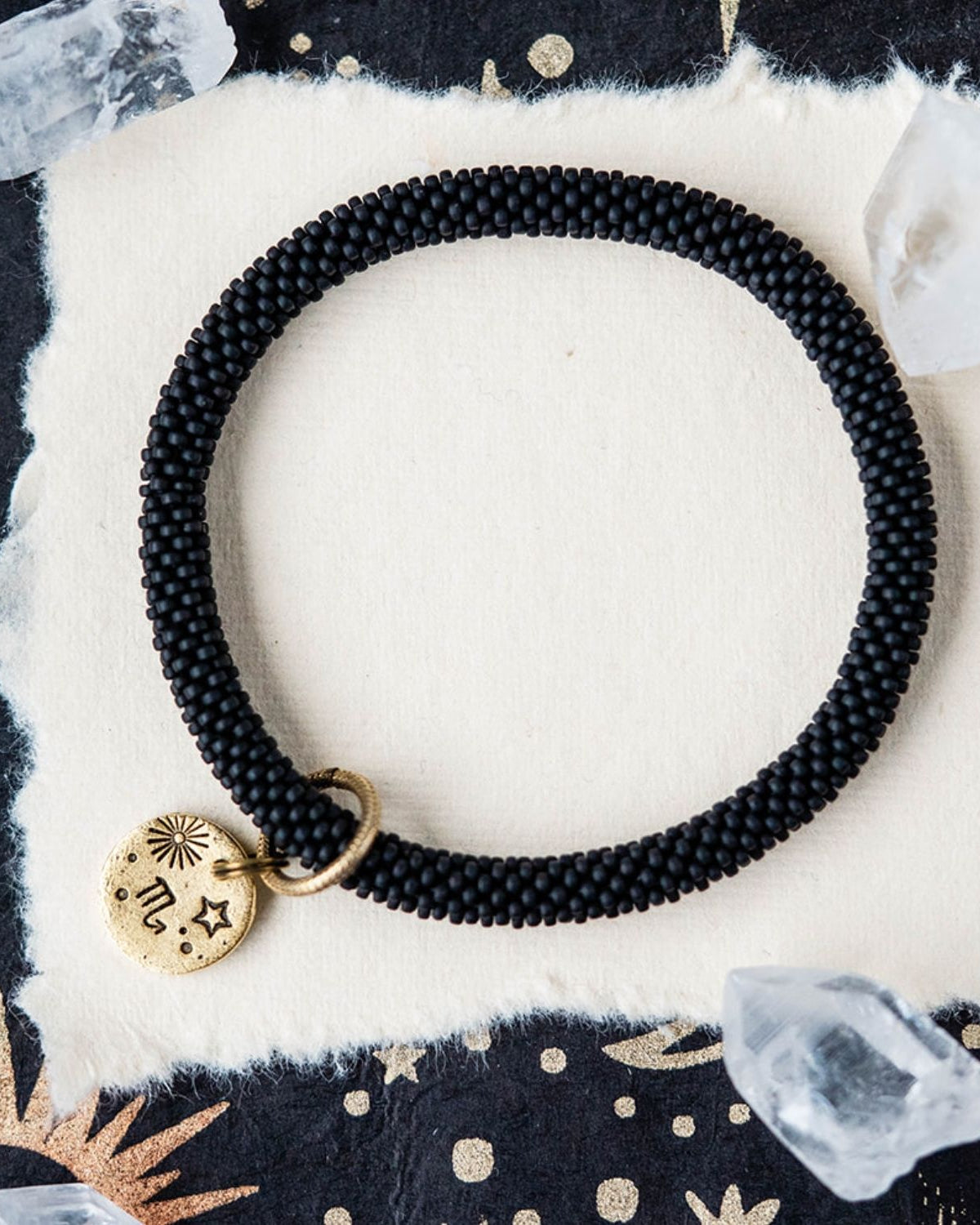 Black beaded bracelet with gold Scorpio zodiac pendant styled with clear crystals and celestial elements