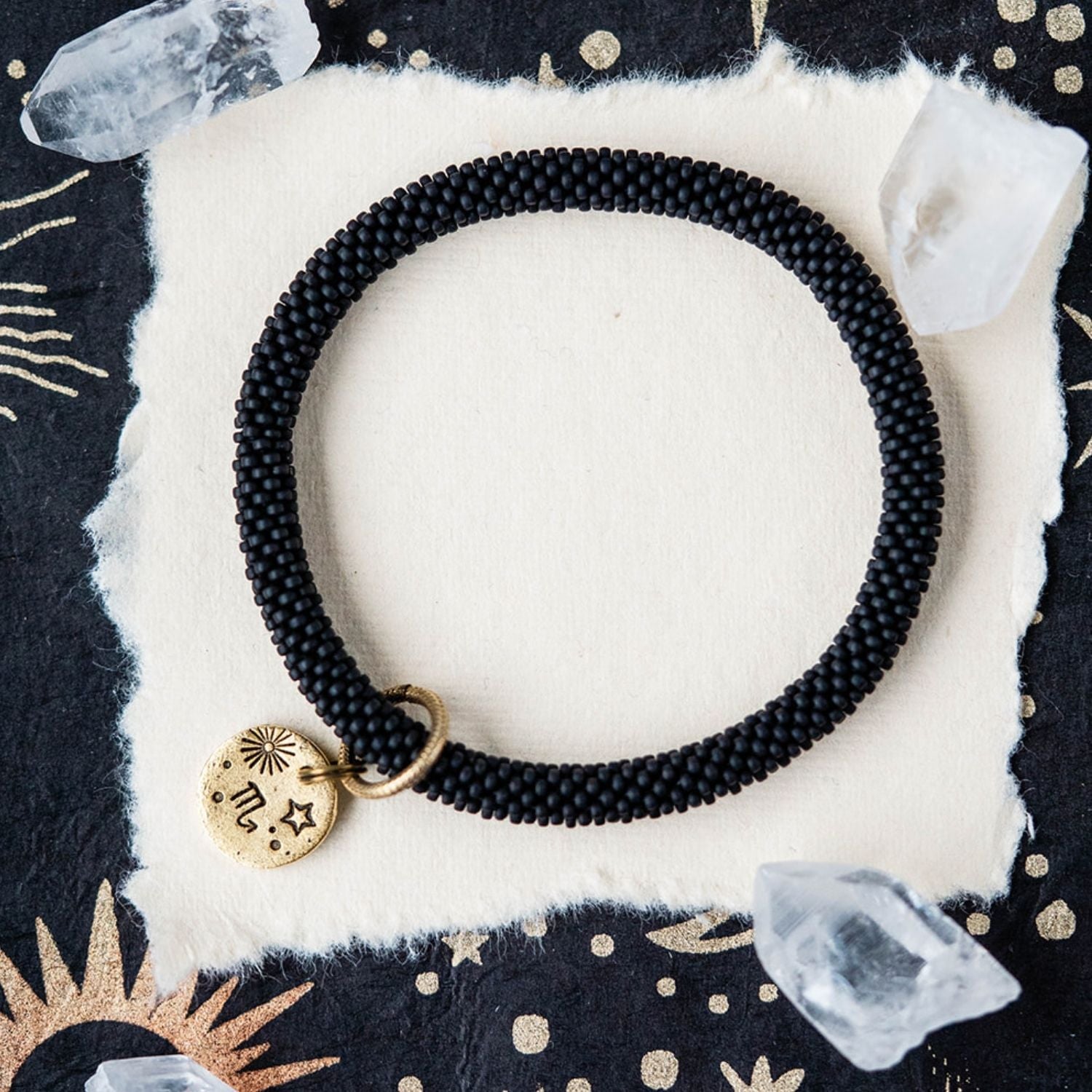 Black beaded bracelet with gold Scorpio zodiac pendant styled with clear crystals and celestial elements
