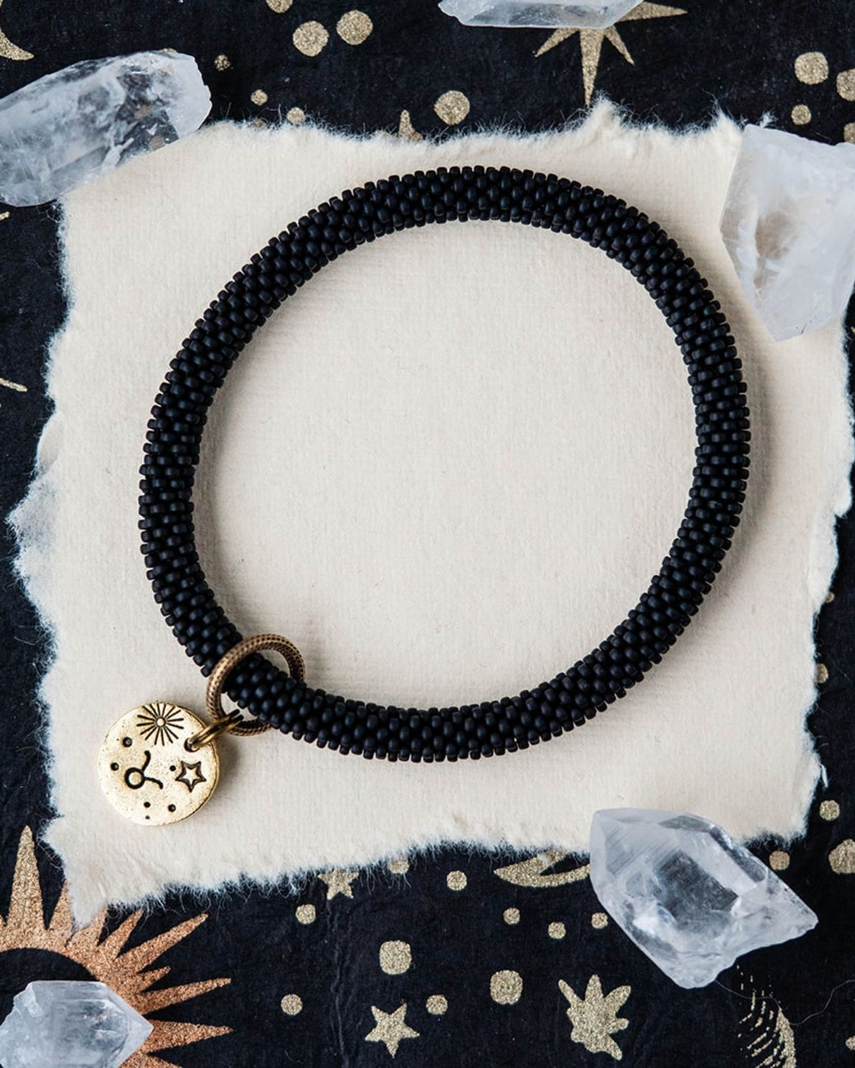 Black beaded bracelet with gold Taurus zodiac pendant styled with clear crystals and celestial elements