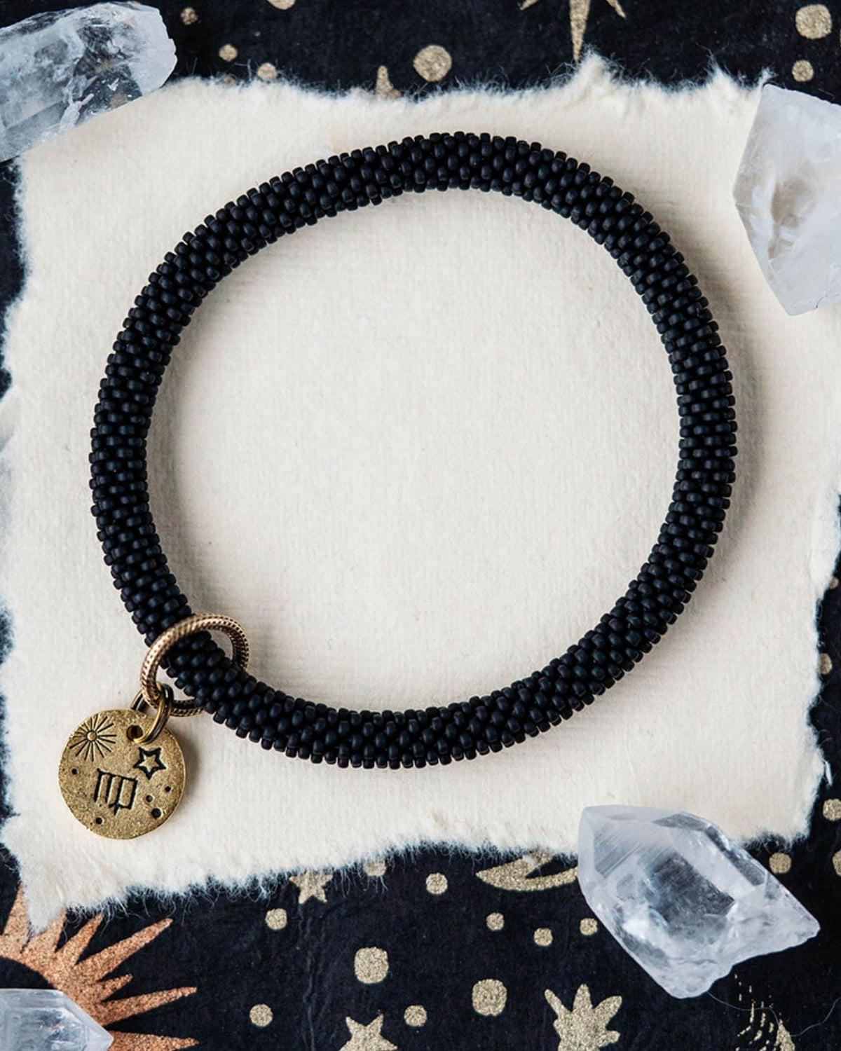 Black beaded bracelet with gold Virgo zodiac pendant styled with clear crystals and celestial elements