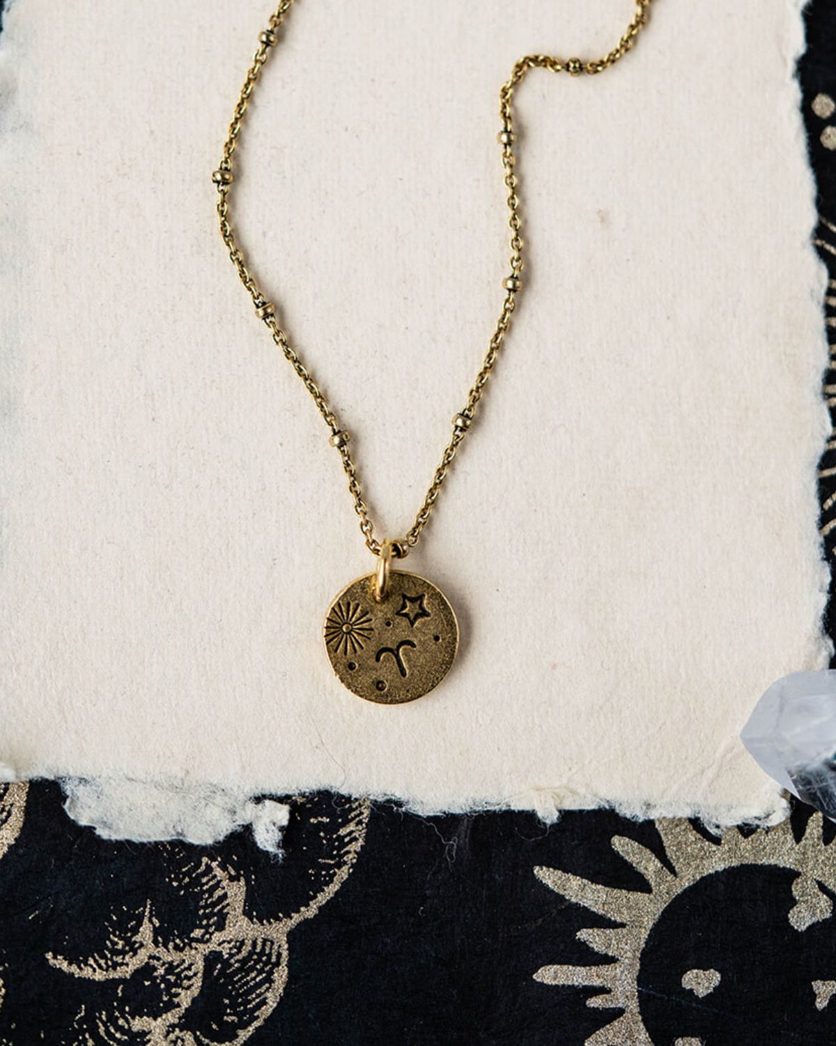 Aries constellation charm necklace with gold disc featuring engraved sun starburst and ram symbols