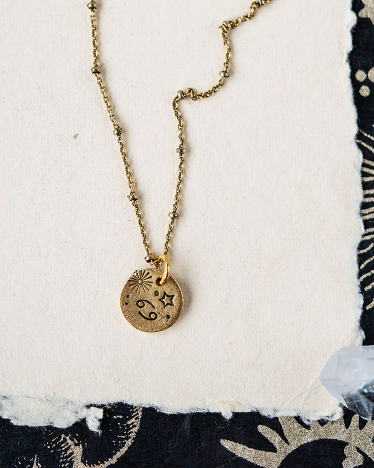 Cancer constellation charm necklace featuring gold disc with engraved crab and star motifs
