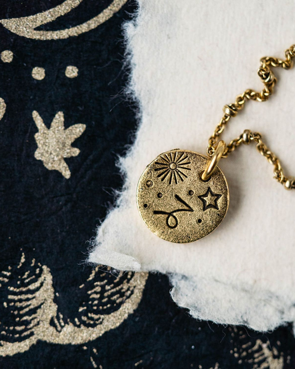 Capricorn constellation charm necklace featuring gold disc with engraved goat and star symbols