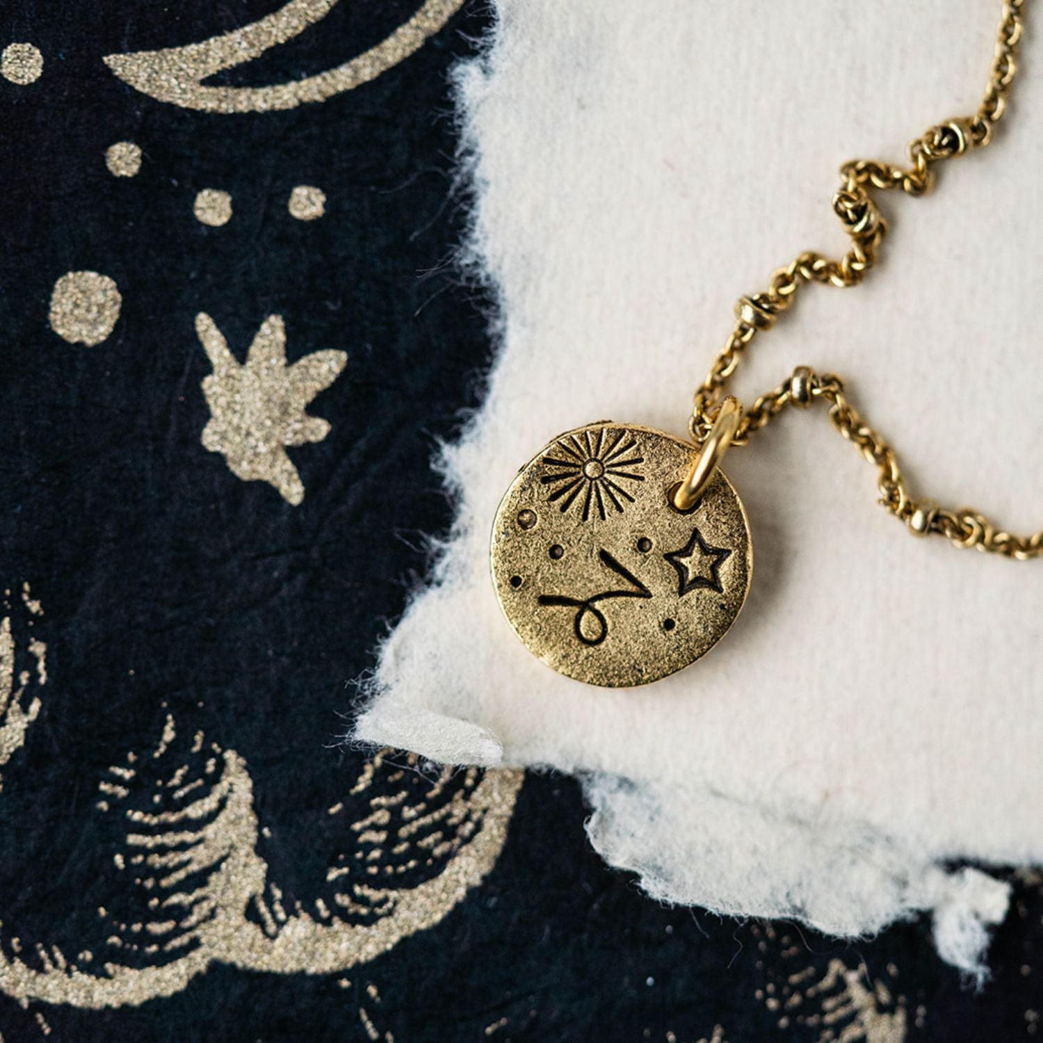 Capricorn constellation charm necklace featuring gold disc with engraved goat and star symbols