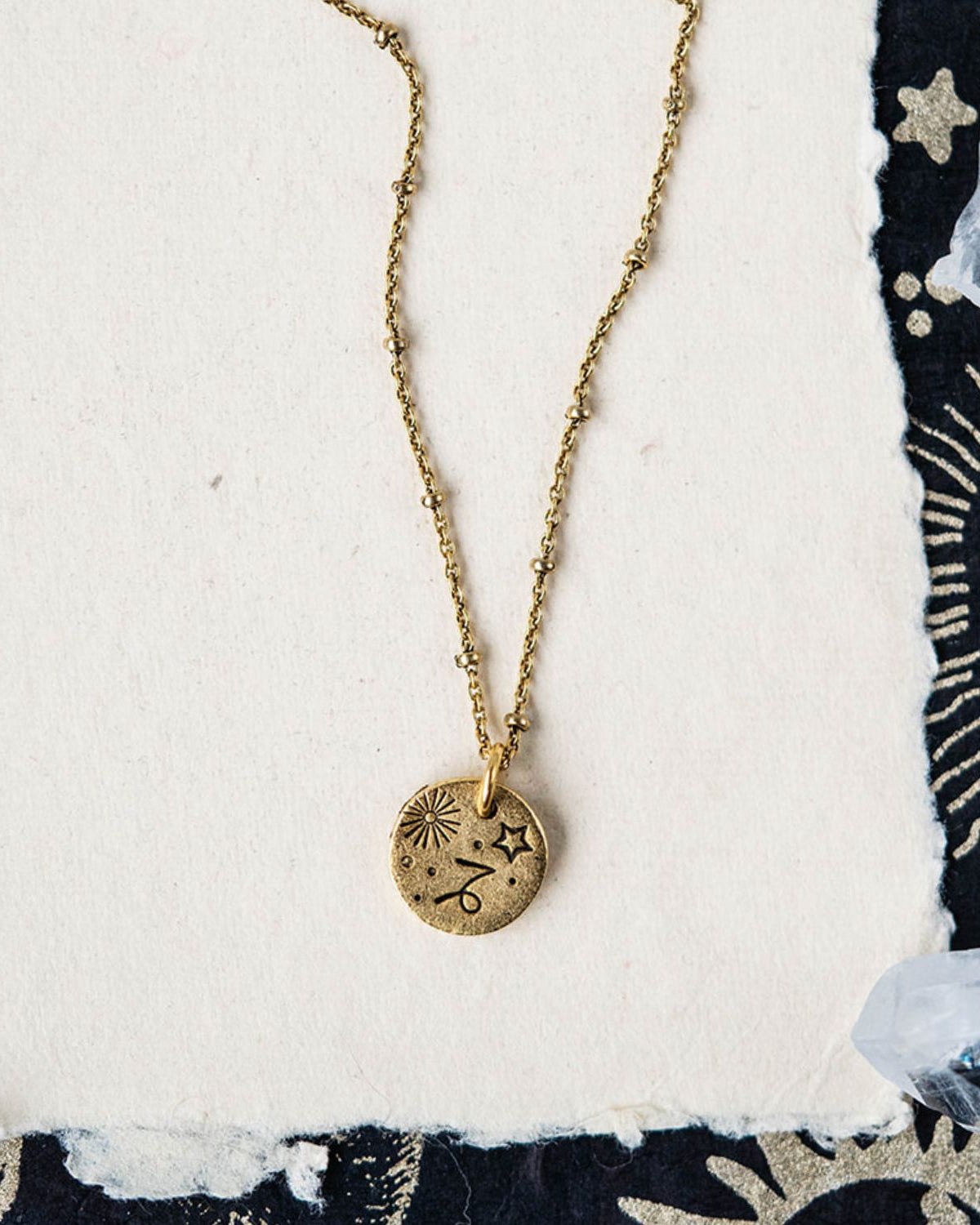Gold Capricorn zodiac pendant necklace with goat horn symbols and celestial motifs on chain