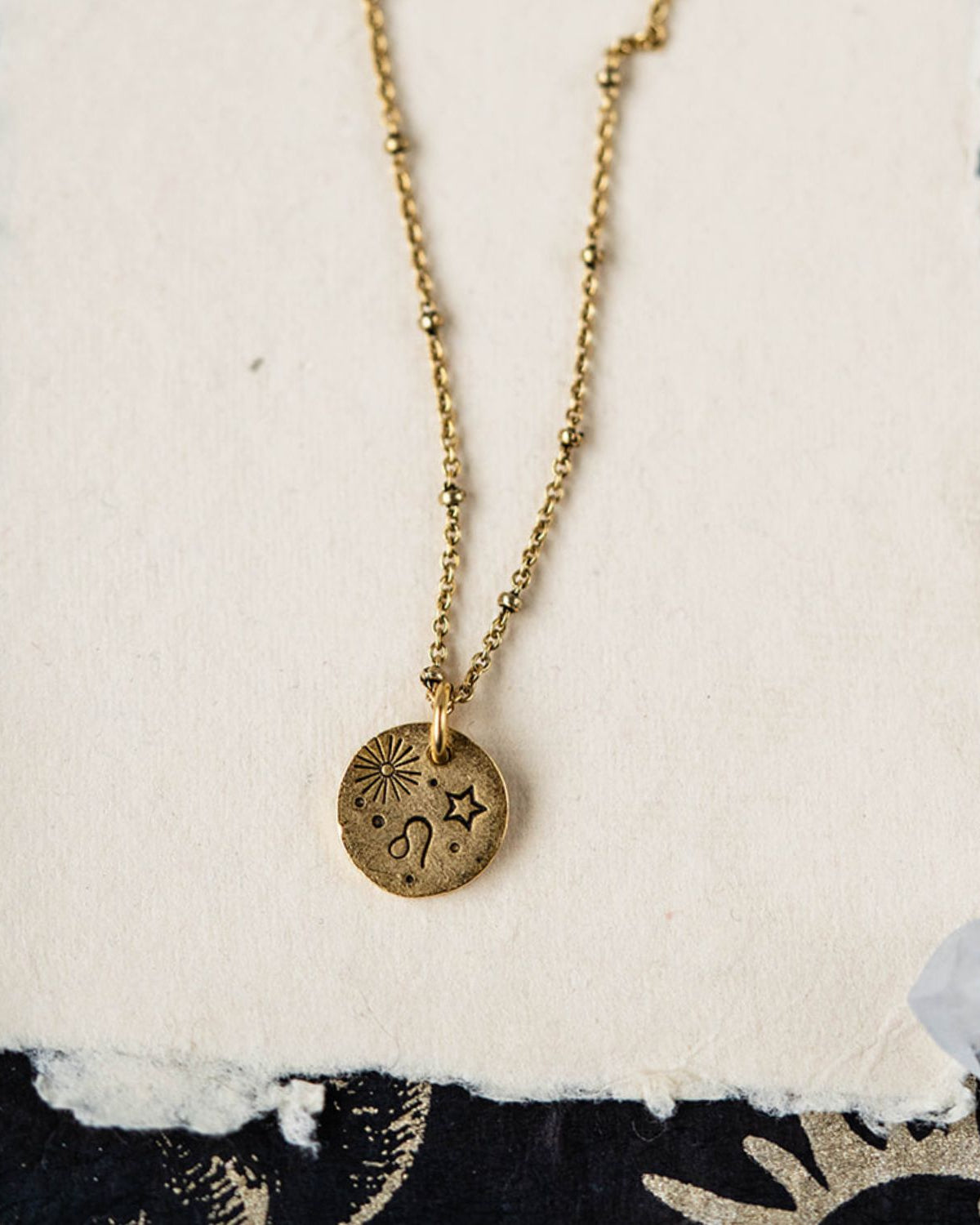 Leo constellation charm necklace featuring gold disc with engraved lion and star motifs