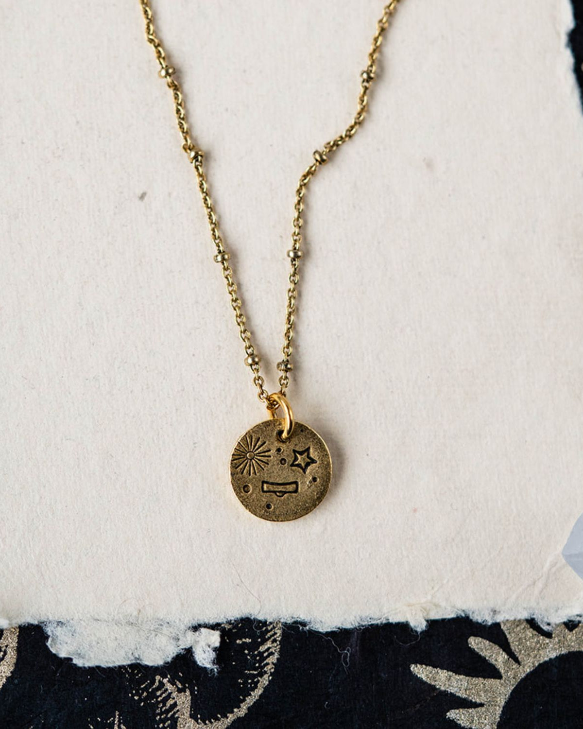 Libra constellation charm necklace featuring gold disc with engraved scales and star motifs
