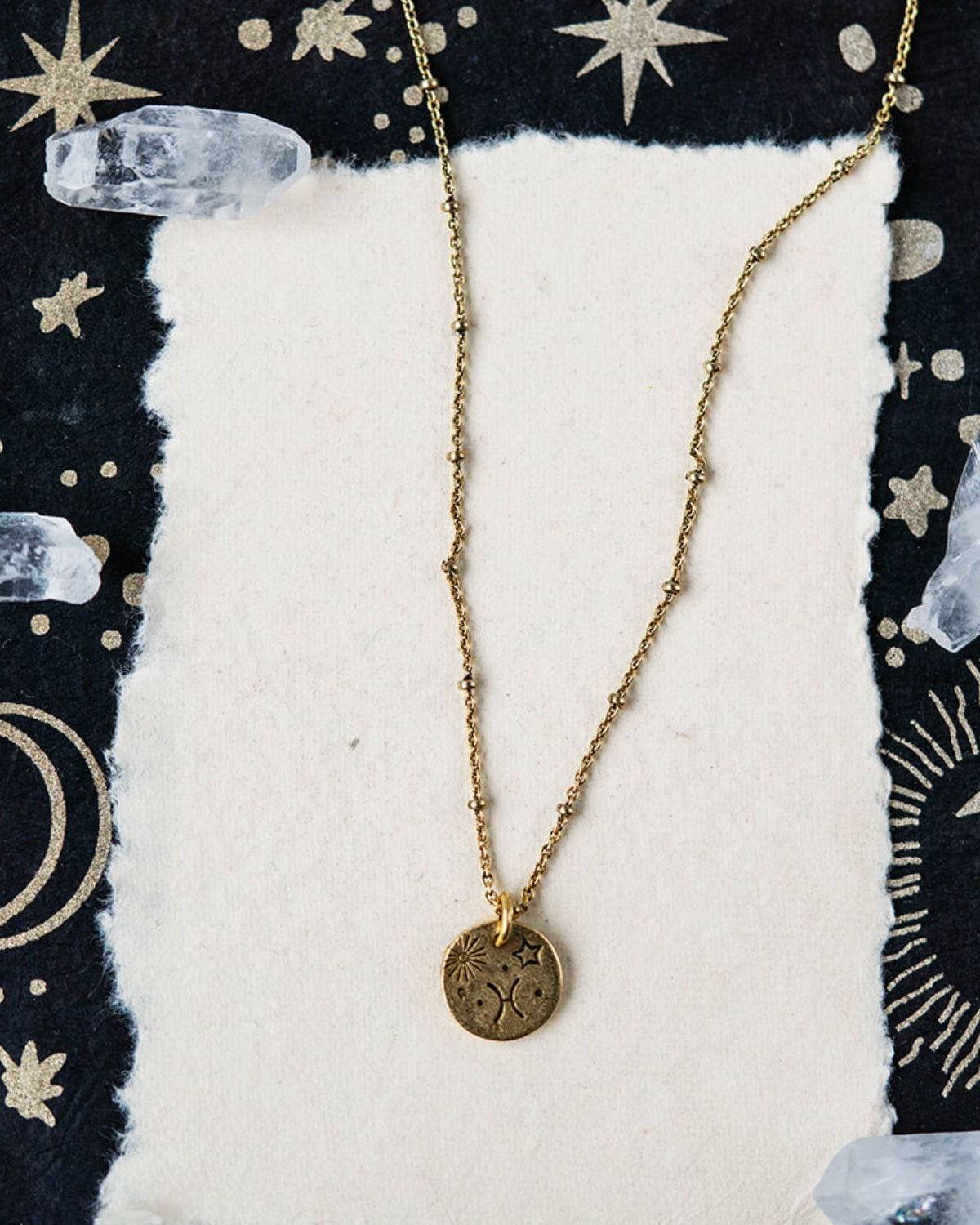 Pisces constellation charm necklace featuring gold disc with engraved fish and star motifs