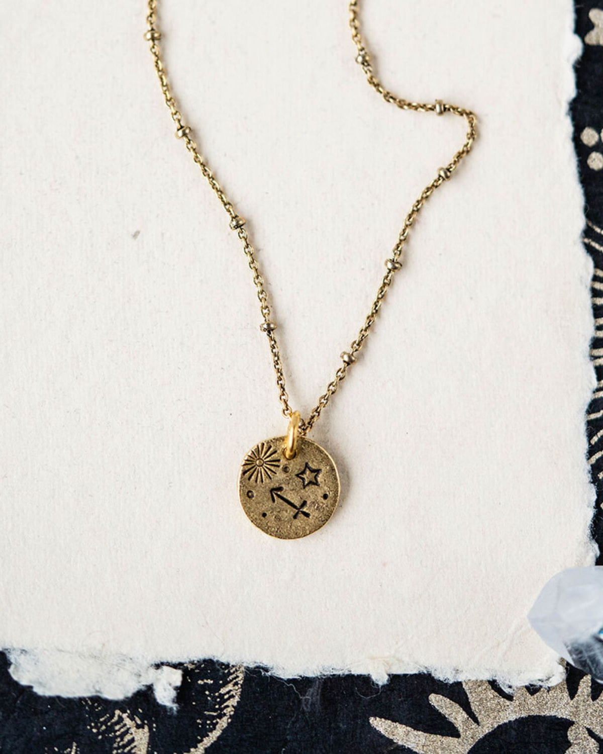 Sagittarius constellation charm necklace featuring gold disc with engraved archer and star motifs