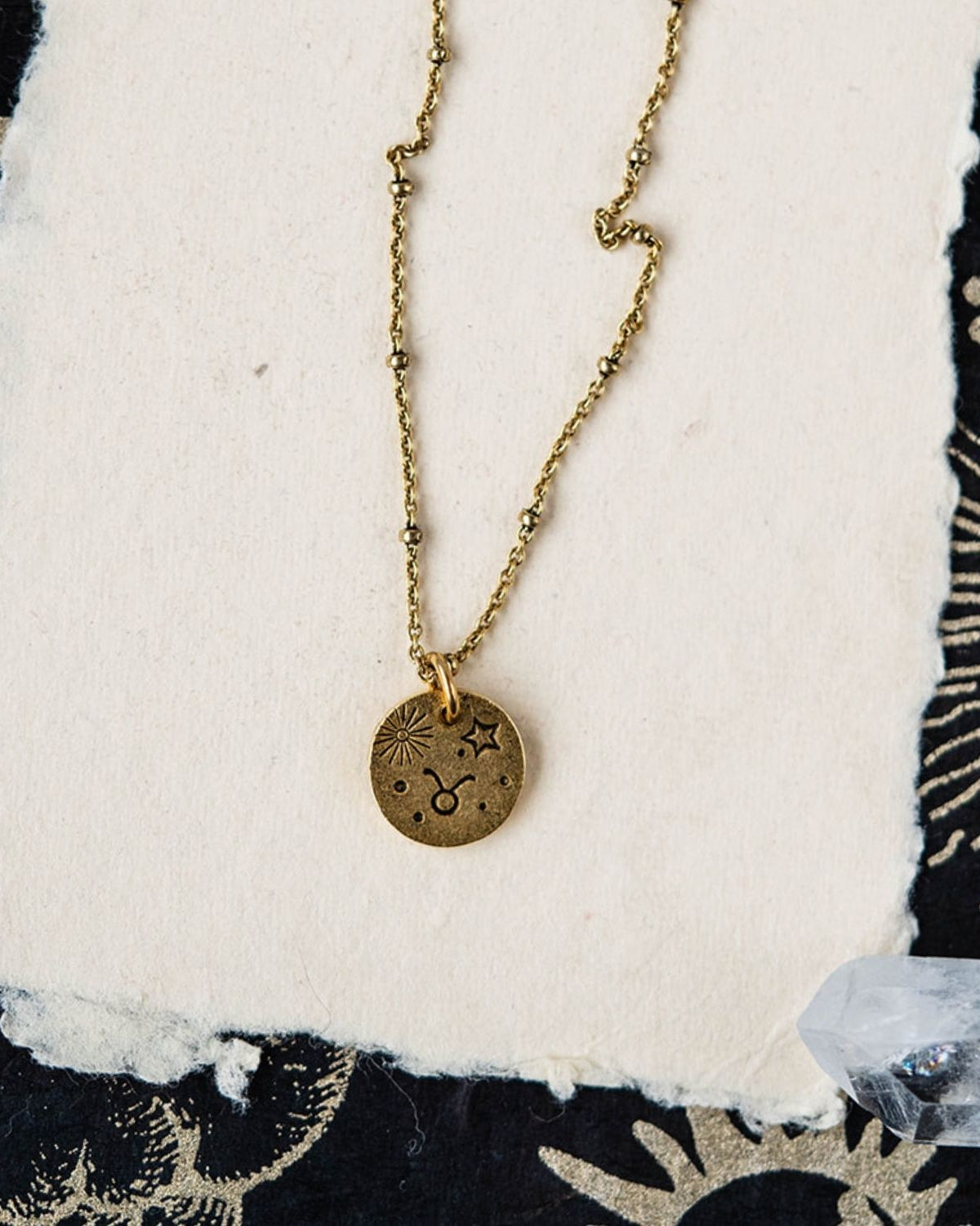 Taurus constellation charm necklace featuring gold disc with engraved bull and celestial symbols