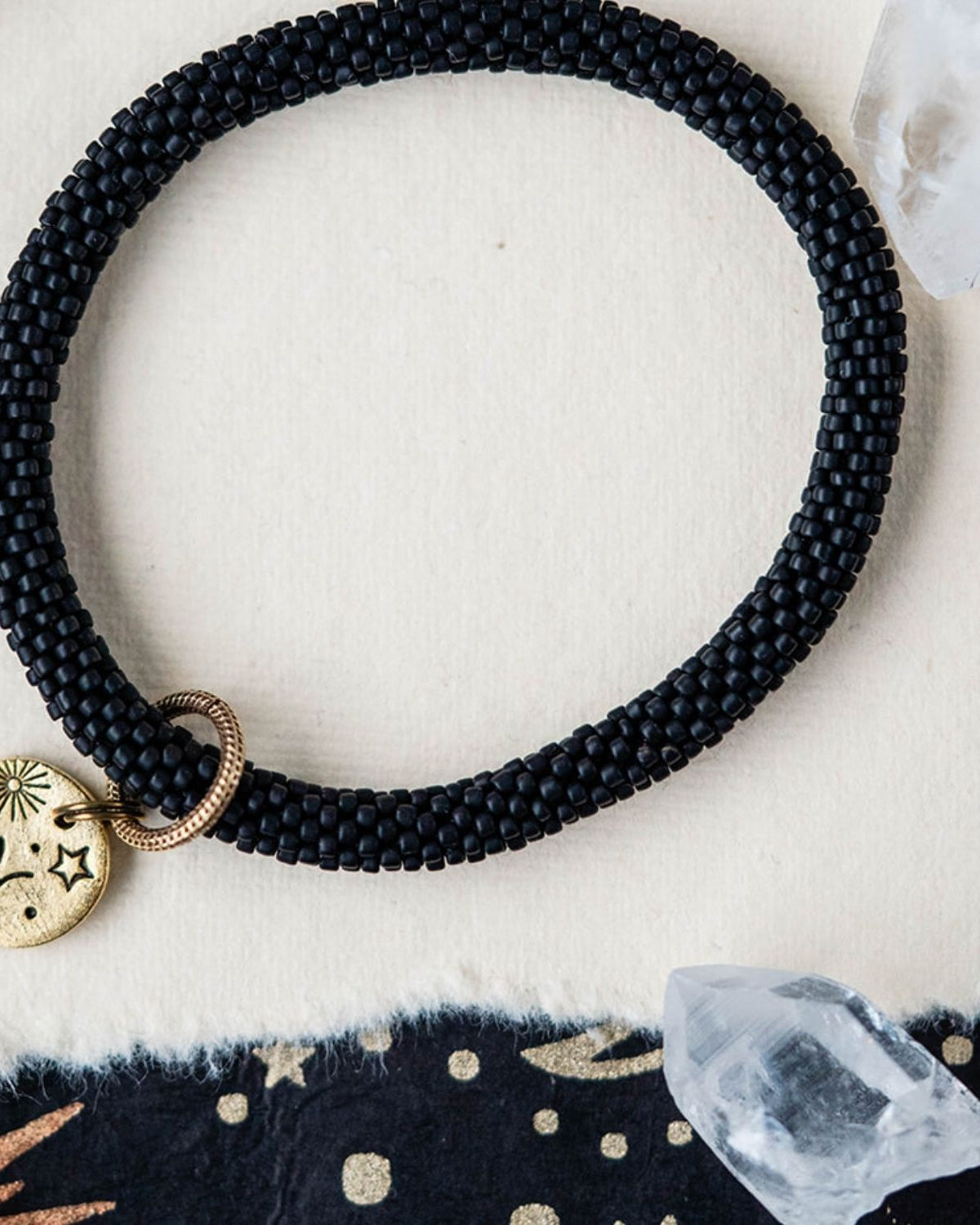 Black beaded bracelet with gold Pisces zodiac pendant styled with clear crystals and celestial elements