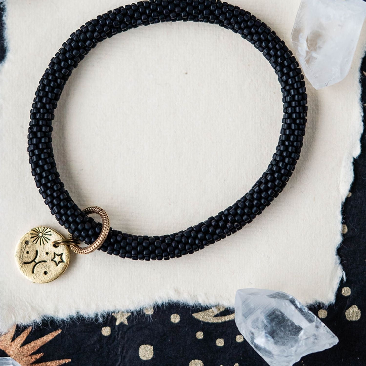 Black beaded bracelet with gold Pisces zodiac pendant styled with clear crystals and celestial elements
