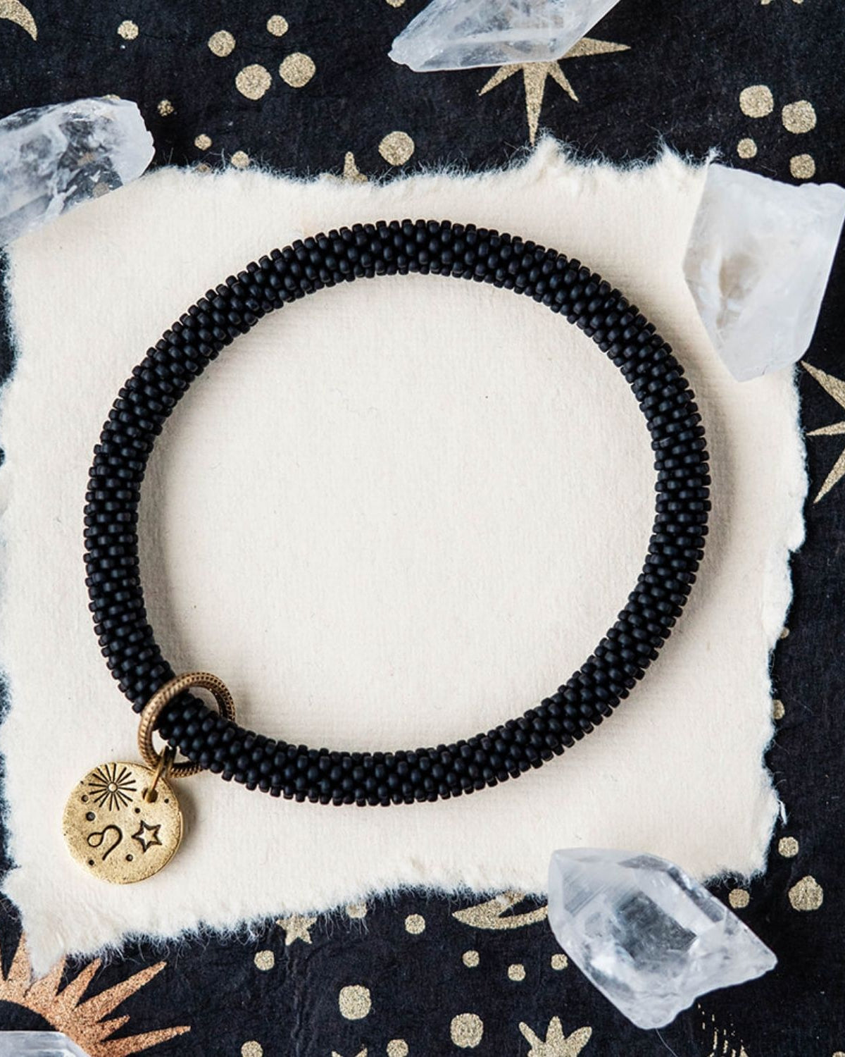Black beaded bracelet with gold Leo zodiac pendant styled with clear crystals and celestial elements