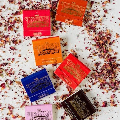The Incense Match collection displayed on bed of dried flowers showing multiple fragrances in colorful matchbooks including spice, match, and floral varieties.