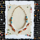 Necklace with colorful beads on a textured card against a black and white patterned background